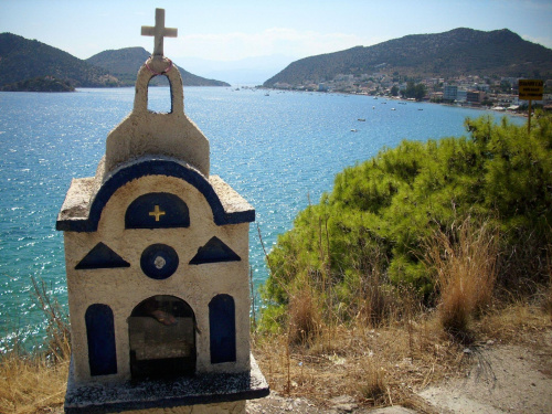 Kapliczka charakterystyczna dla greckiego krajobrazu.W tle Tolo.